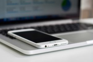 white smart phone resting on an open laptop.